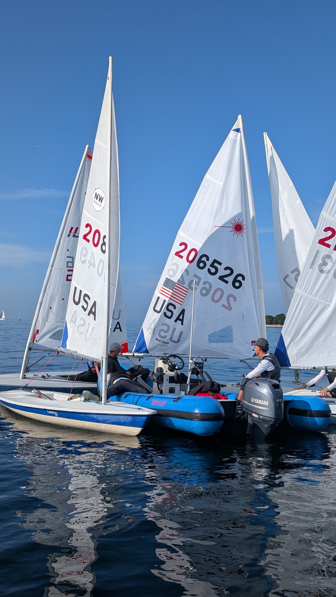 A group of sailors gathered around the coach boat on a very light wind day.